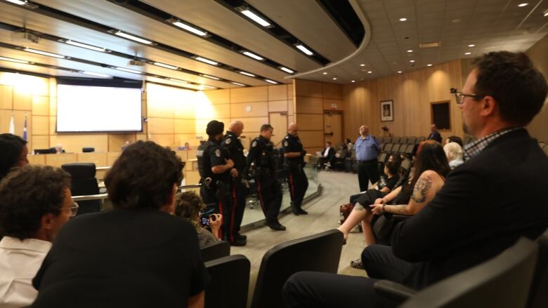 Councillors Dan LeBlanc, Shannon Zachidniak and Andrew Stevens look on as Regina police officers attempt to encourage protestors to leave the chambers of city hall