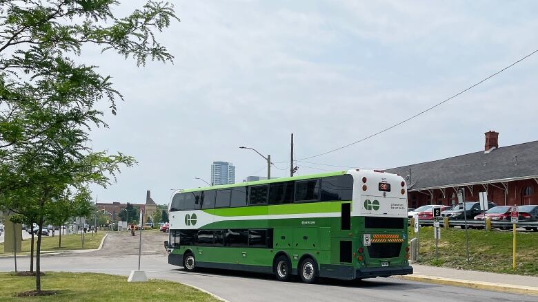 Green and white bus in front of old train station