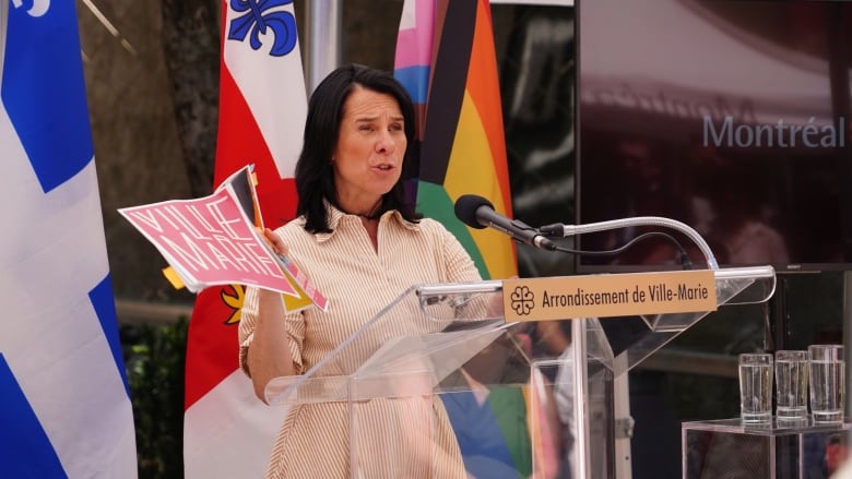 Valrie Plante speaks at a podium during a news conference outdoors and is holding the city's plan. 