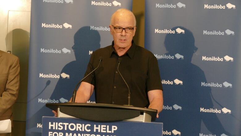 A man stands at a podium speaking into a microphone.