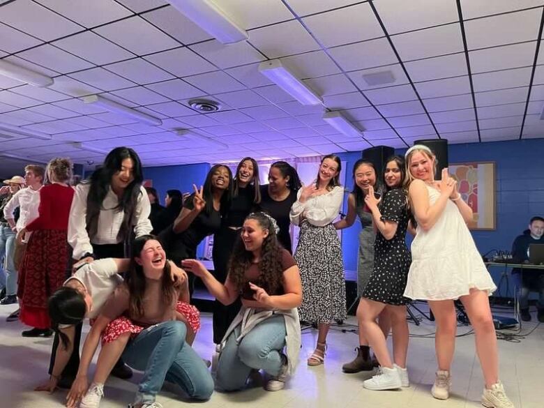 A group of students laugh and pose for the camera in an indoor, school environment.