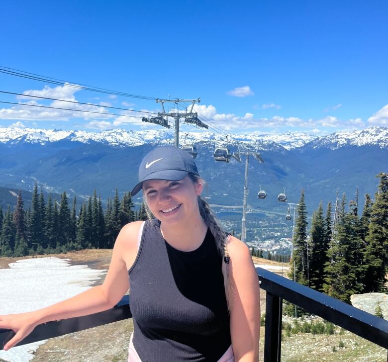 A woman stands in front of a mountain vista complete with chairlift.