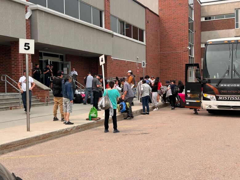 People disembarking from a bus carrying light luggage. 