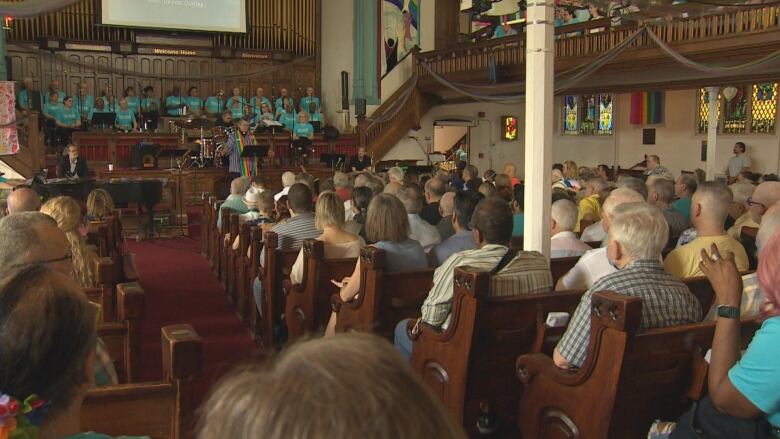 Churchgoers sit in a church listening to someone speak.