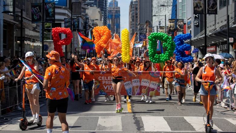 Marchers waving and carrying flags take part in a Pride parade.