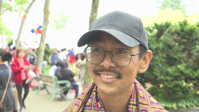 A young man with a cap and glasses speaks to the camera.