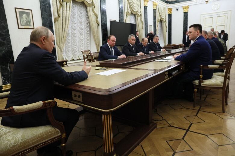 People are seen seated around a long rectangular table.