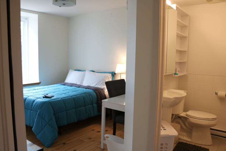 Picture of a bedroom in a subsidized housing project. The room is furnished with new furniture. A bed and washroom are seen in the shot. 