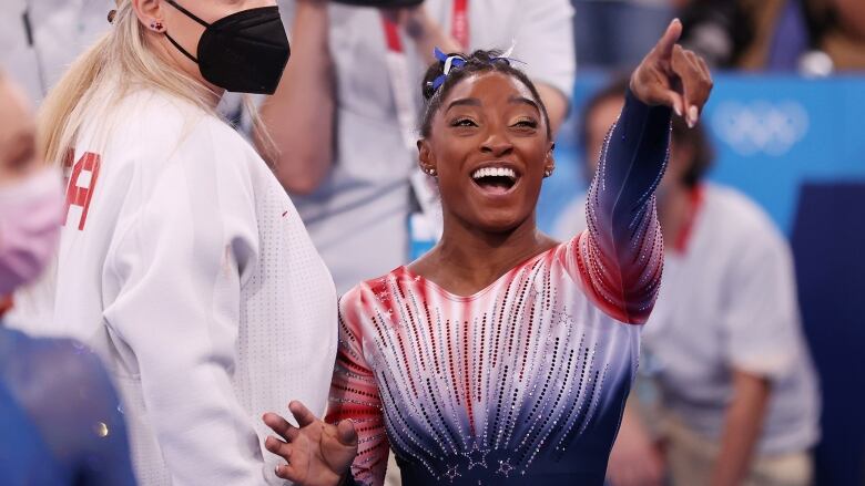 A gymnast smiles and points.