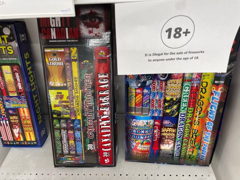 fireworks sit on a store shelf behind a sign warning they can't be sold to anyone under 18