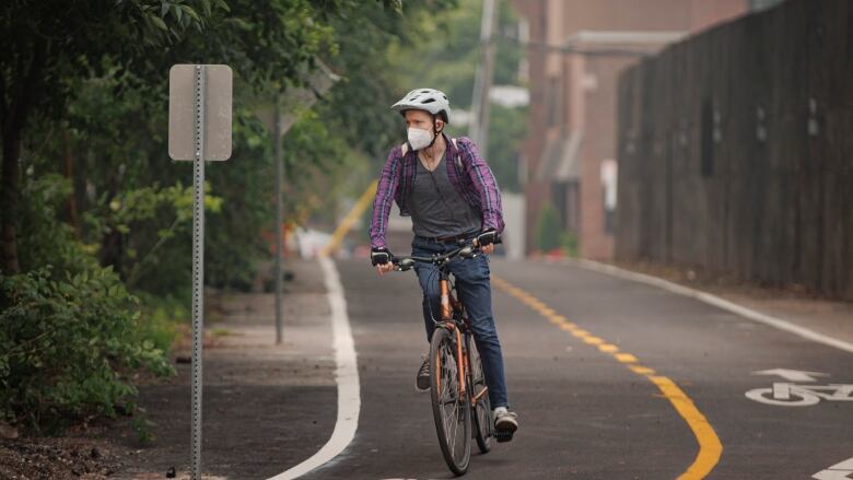 A cyclist wearing a mask commutes through Toronto as smoke from wildfires burning across the country clouds the air on June 28, 2023.