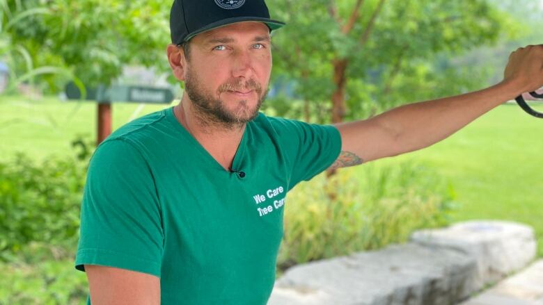 A man wearing a green tshirt with a black baseball cap. 