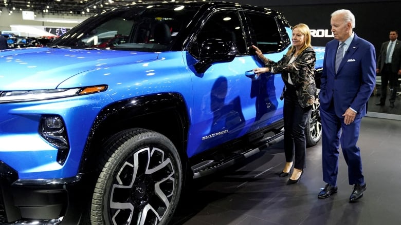 Standing on floor of auto show in front of blue car