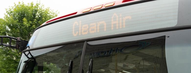 The electric sign at the front of a bus reads 'clean air.'