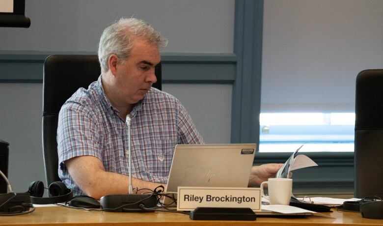 A man sits behind a laptop.