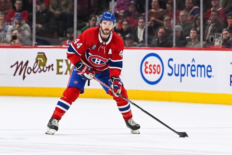 A men's hockey player leans over as he prepares to pass the puck.