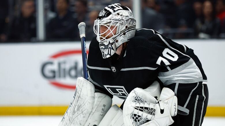 A men's goaltender hunches over, watching the play.