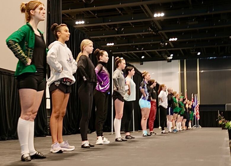 More than a dozen dancers are lined up on the stage. 