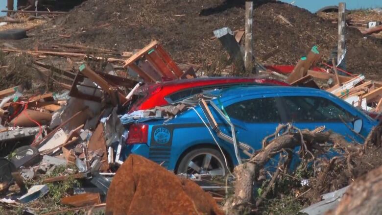 A damaged car and house are pictured following a tornado.