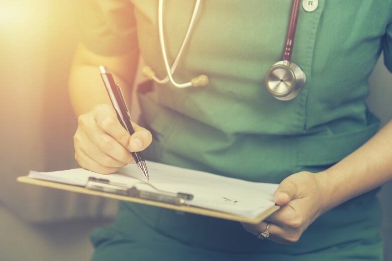 Closeup of a person in scrubs wearing a stethoscope.