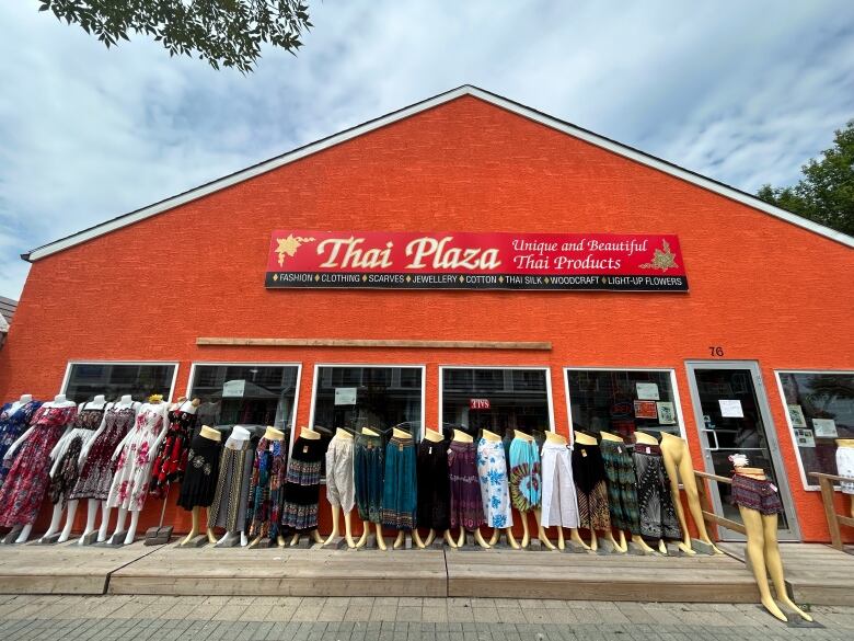 A storefront with clothing and mannequins in front of its window. 