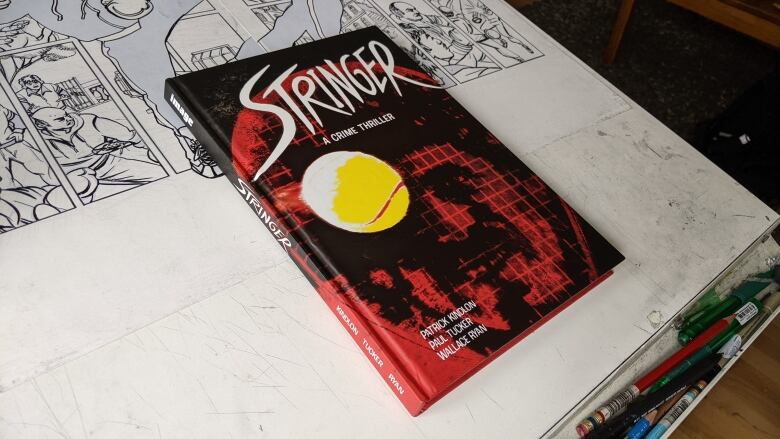 A graphic novel sits on an artist's drawing table.