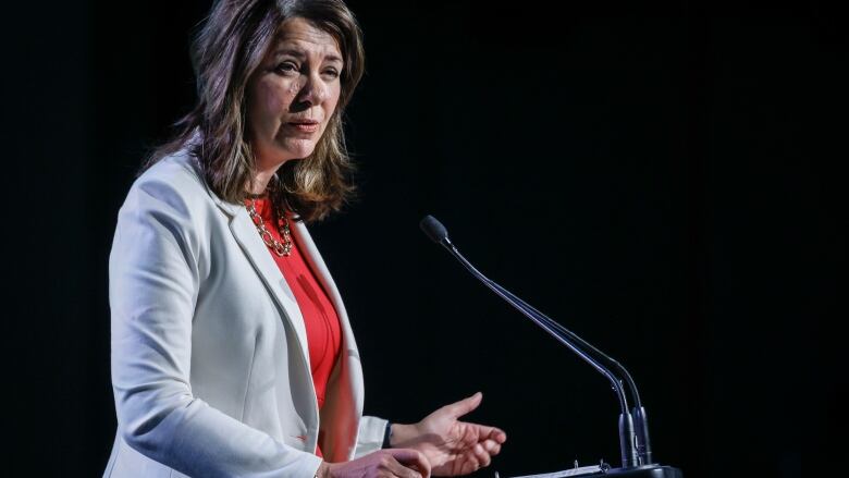 A woman stands at a lectern giving a speech.