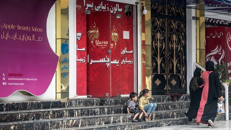 Women walk past a beauty salon in Kabul on Tuesday.