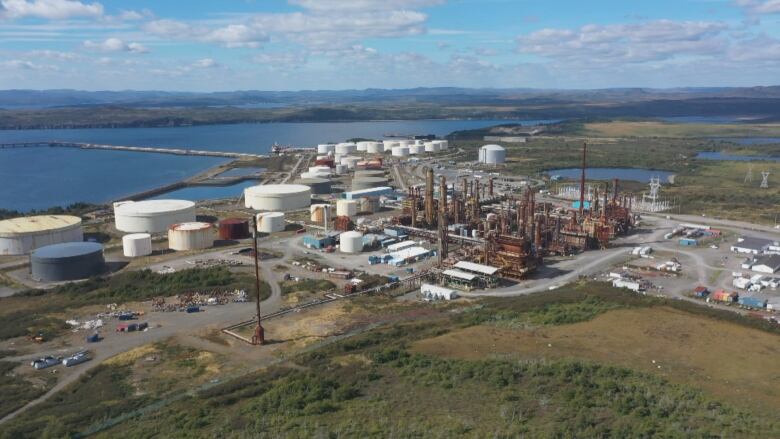 A refinery and large tanks are picture from the air in a drone image.