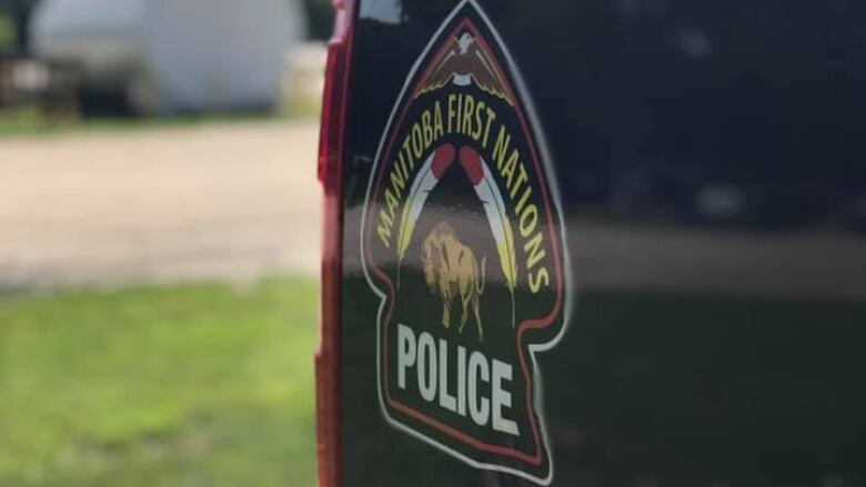 A closeup shows the Manitoba First Nations Police Service logo on a black vehicle.