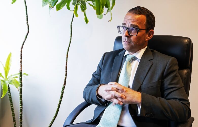 A man in a suit and tie is seated, looking out through the window. 