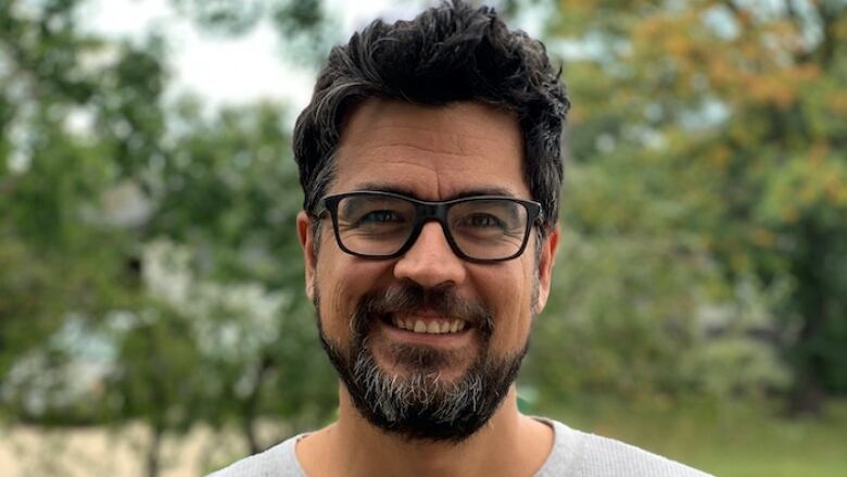 A man with glasses and a beard smiles at the camera. 