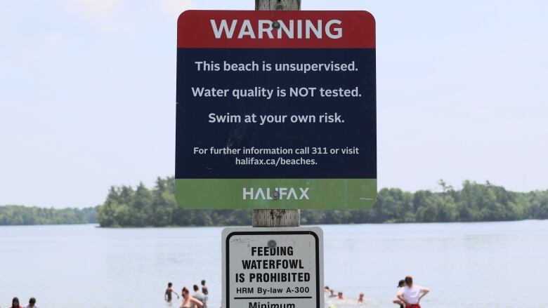 a sign in front of a lake with people in it.