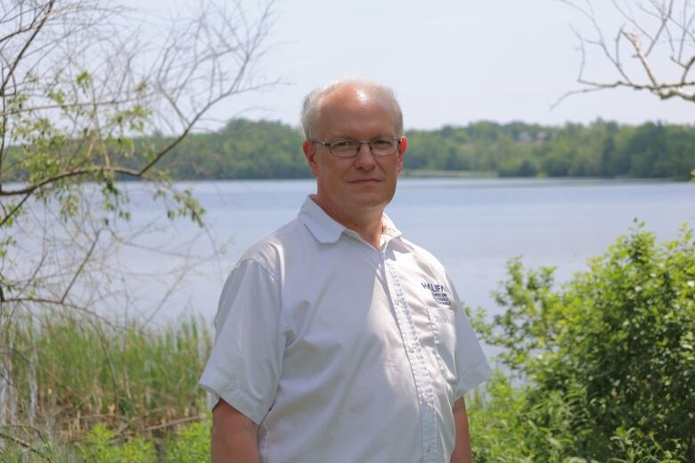 A man stands next to a lake.