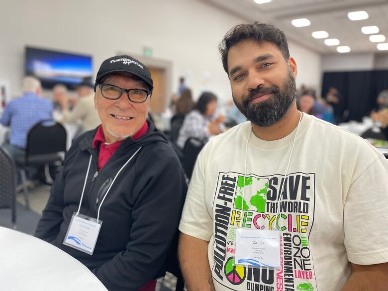 Two men at a conference sit at a table.