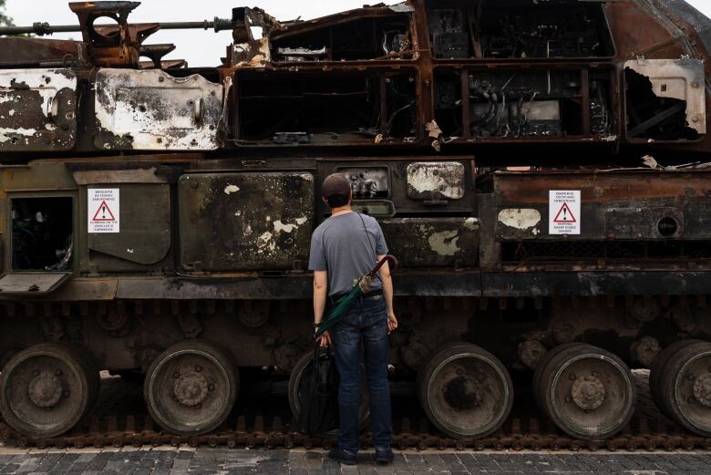 A man in a T-shirt looks at a tank.