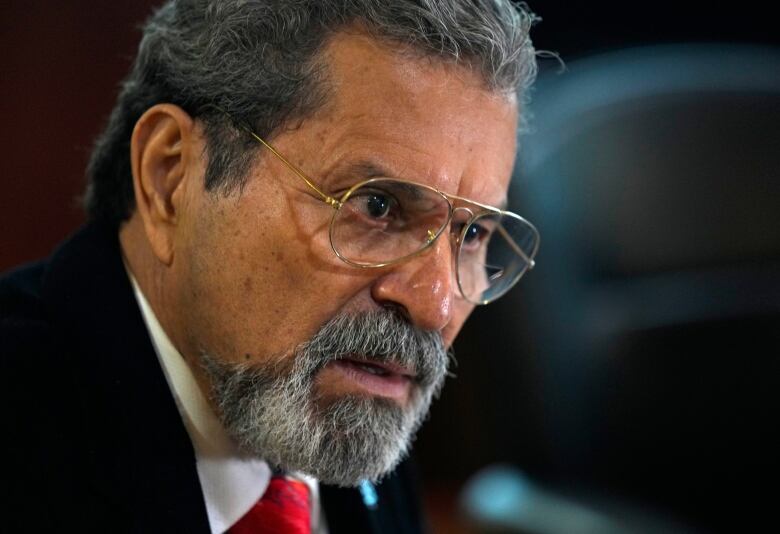 A close-up of a bespectacled man with a gray goatee.