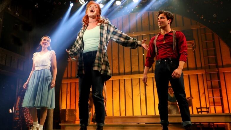 Anne Shirley at centre stage in Anne of Green Gables: The New Musical, flanked by Gilbert and Diana Barry.