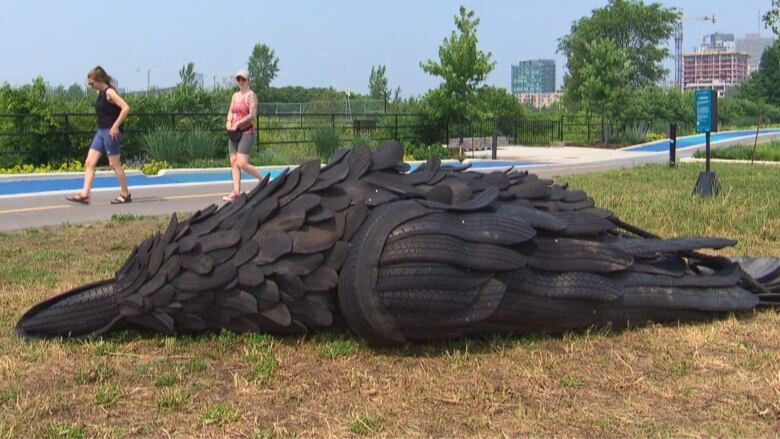 People walk past the crow sculpture in Ottawa's LeBreton Flats neighbourhood.