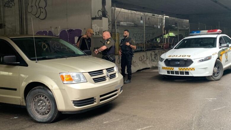 A man and two provincial police officers speak between cars.