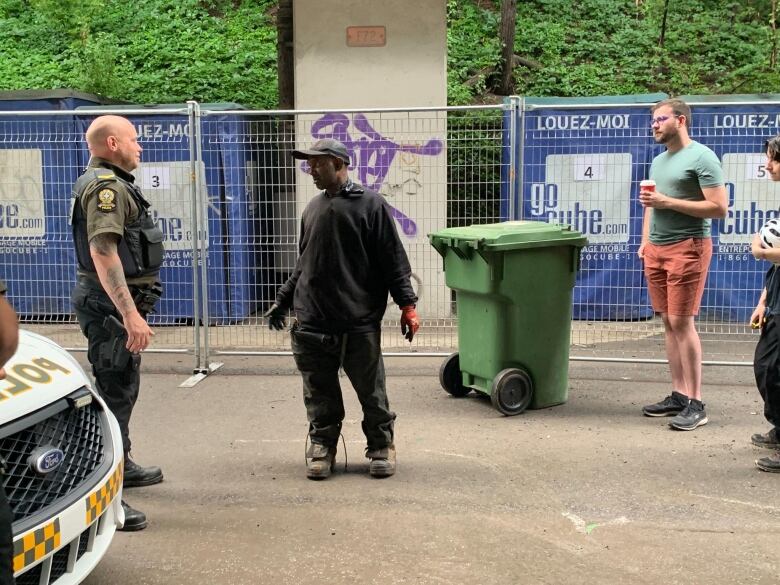 A man stands between a provincial polie officer and a couple of people. 