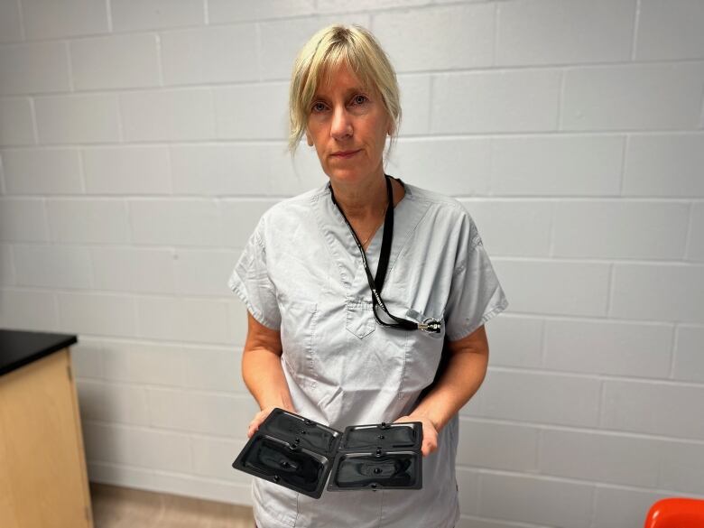 A woman in scrubs holds a glue trap