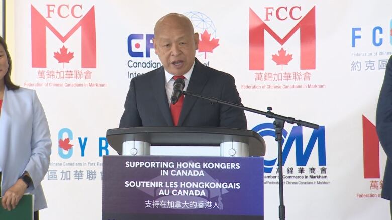 A man in suit speaks behind a podium and a microphone.