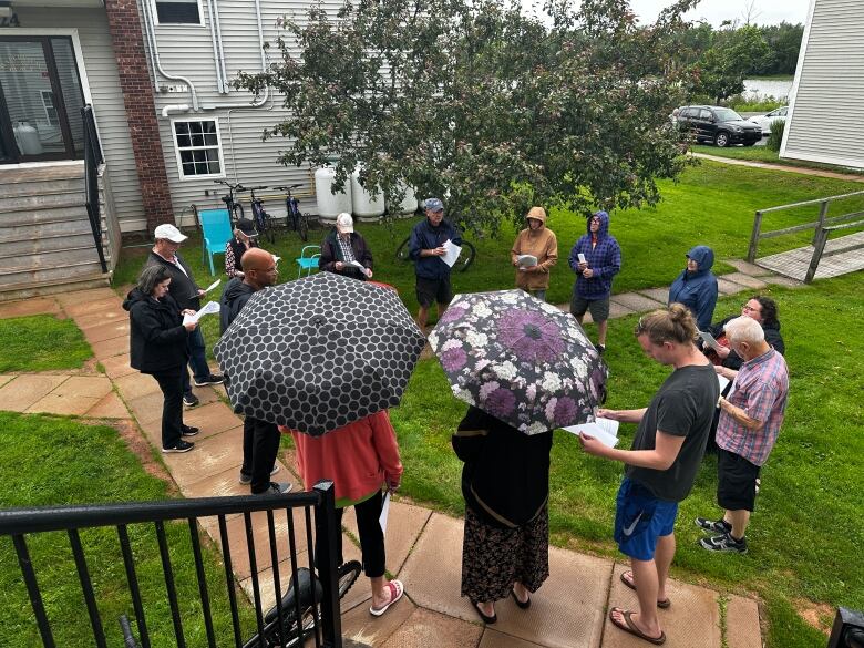 People gathered in a circle outdoors outside of the Waterview Heights units in Summerside.