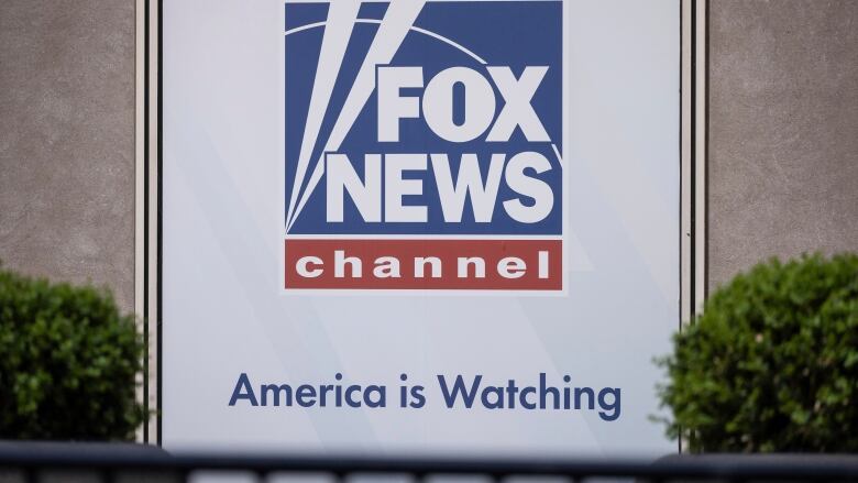 A logo reading, 'Fox News channel, America is watching,' is shown on the side of a building.