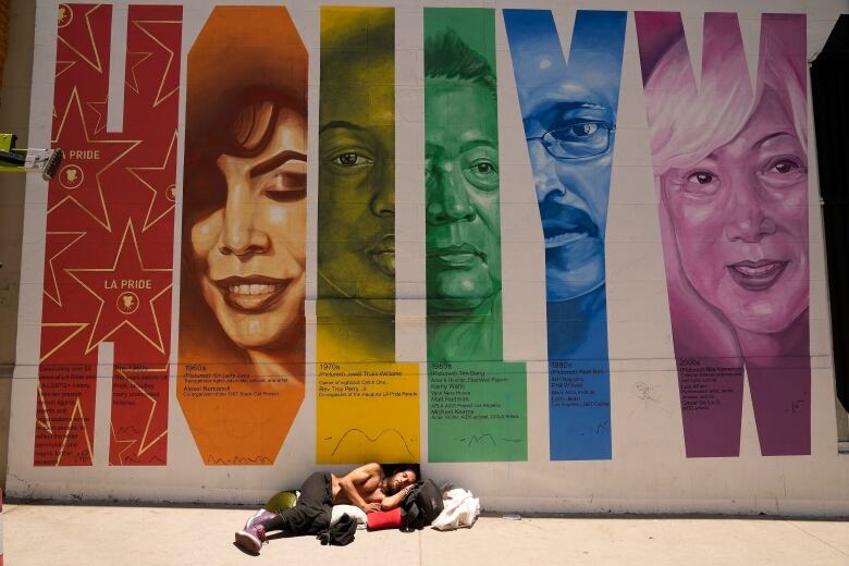 A homeless man sleeps under the sun in the Hollywood district of Los Angeles