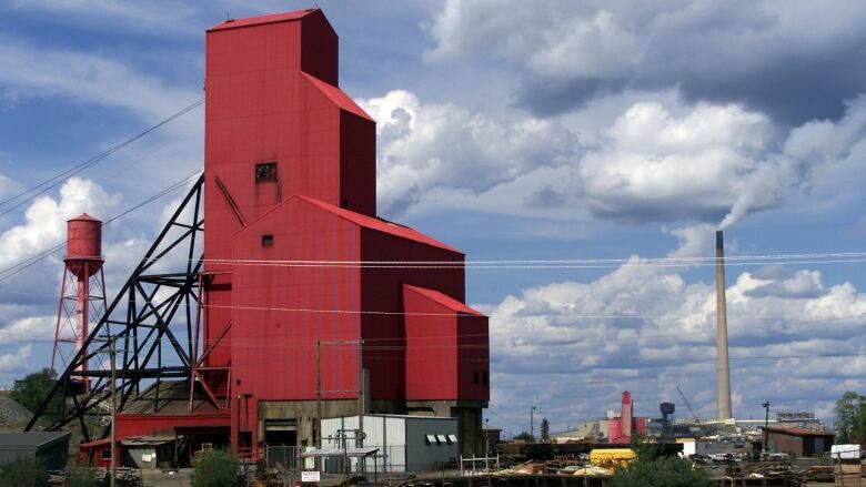 Mining shafts and a smokestack are seen on a summer day.