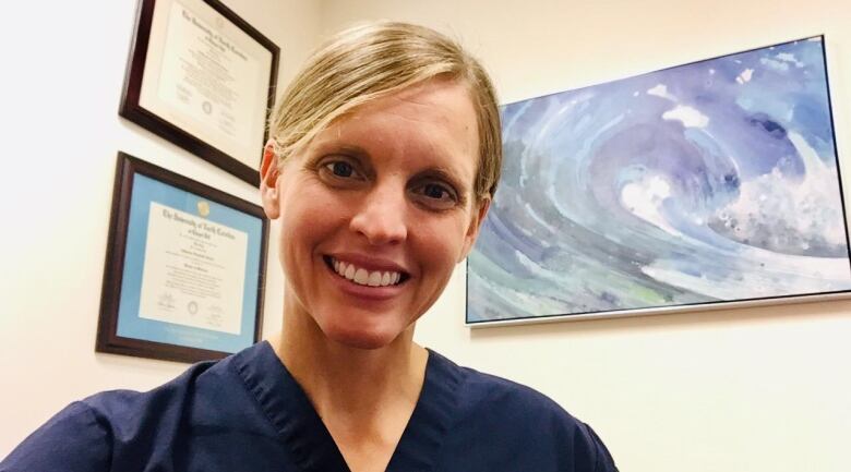 Female physician wearing scrubs in an office.