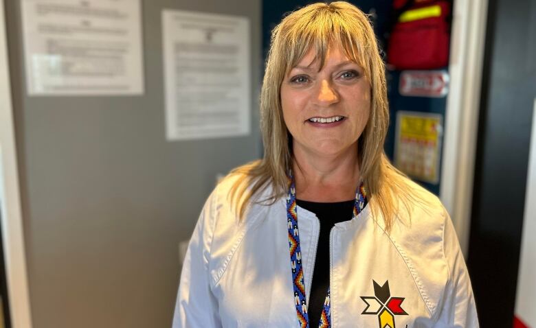 Crissy Riley, a smiling woman with long blond hair, stands in a medical office. 