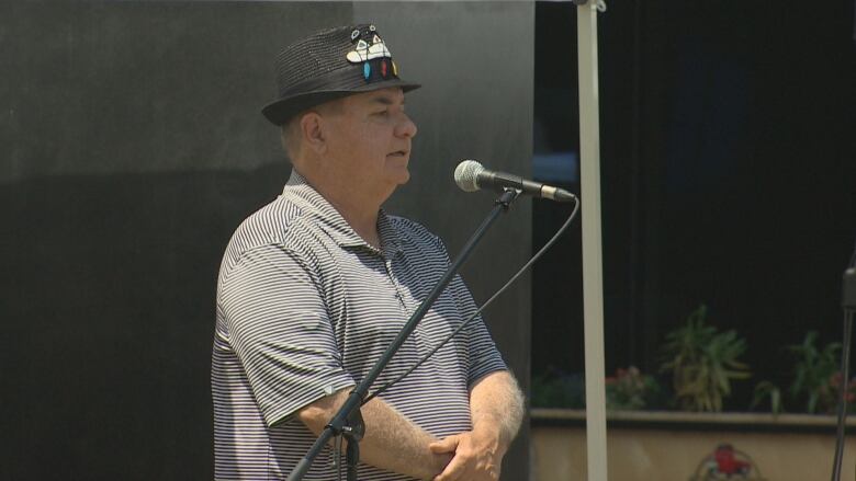 A man with a NAIG 2023 cap is seen speaking into a microphone.